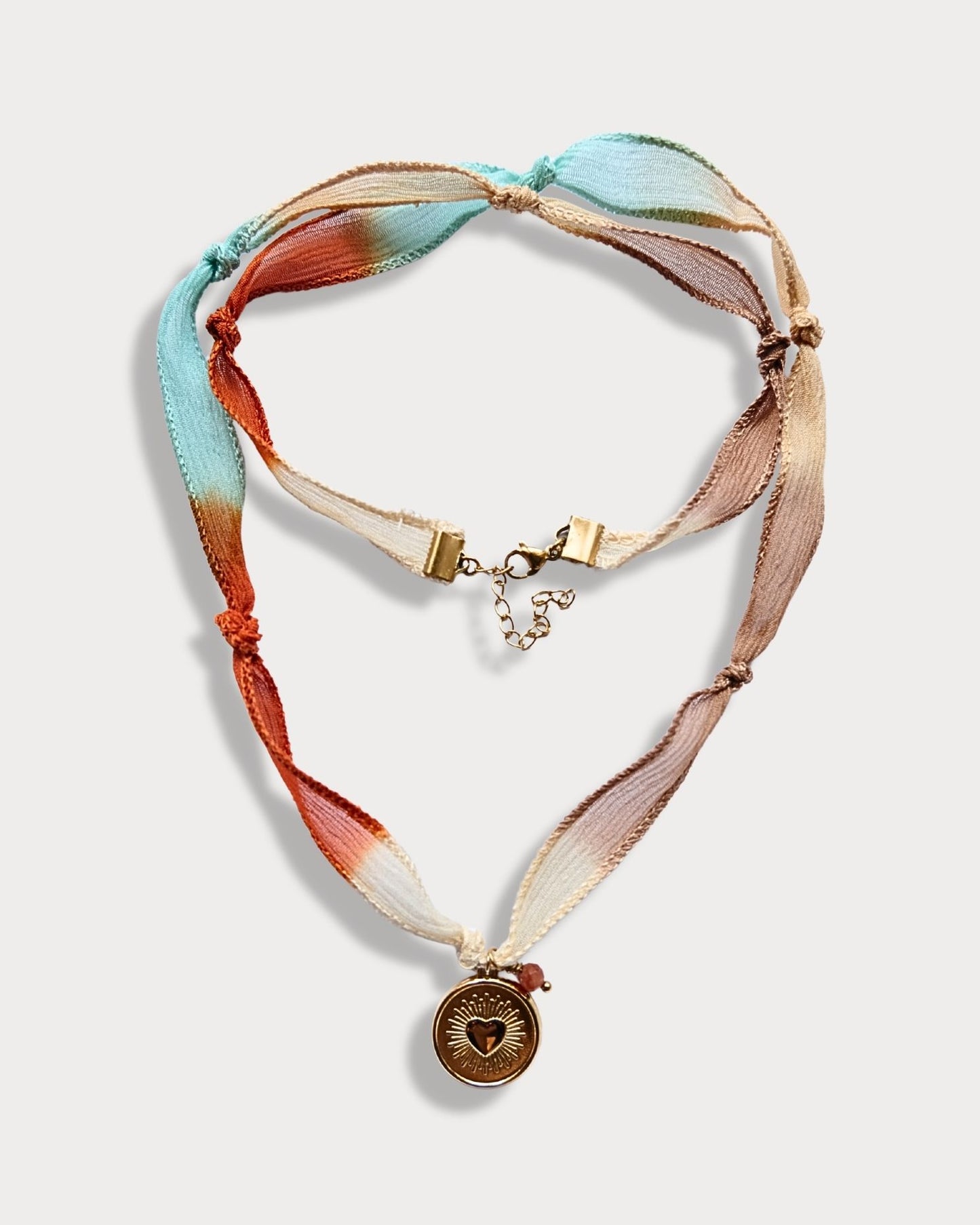 Collana in seta annodata azzurro, arancio e rosa con pendente a forma di cuore e pietra del sole