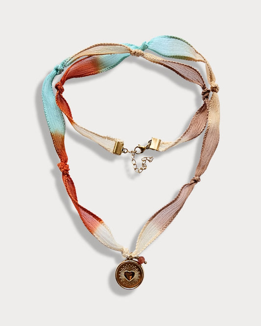 Collana in seta annodata azzurro, arancio e rosa con pendente a forma di cuore e pietra del sole