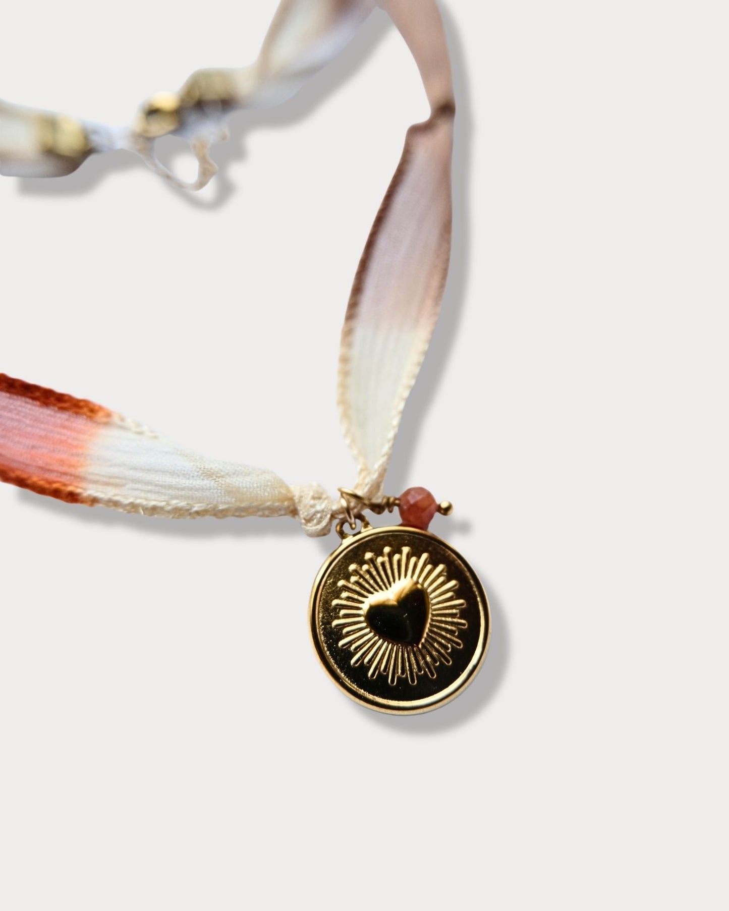Collana in seta annodata azzurro, arancio e rosa con pendente a forma di cuore e pietra del sole