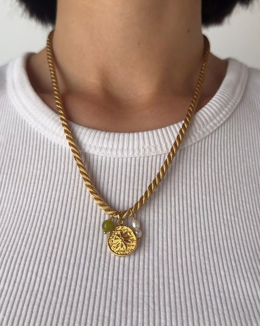 Collana in cordino intrecciato color ocra con pendente a forma di sole e pietra di peridoto e perle di fiume